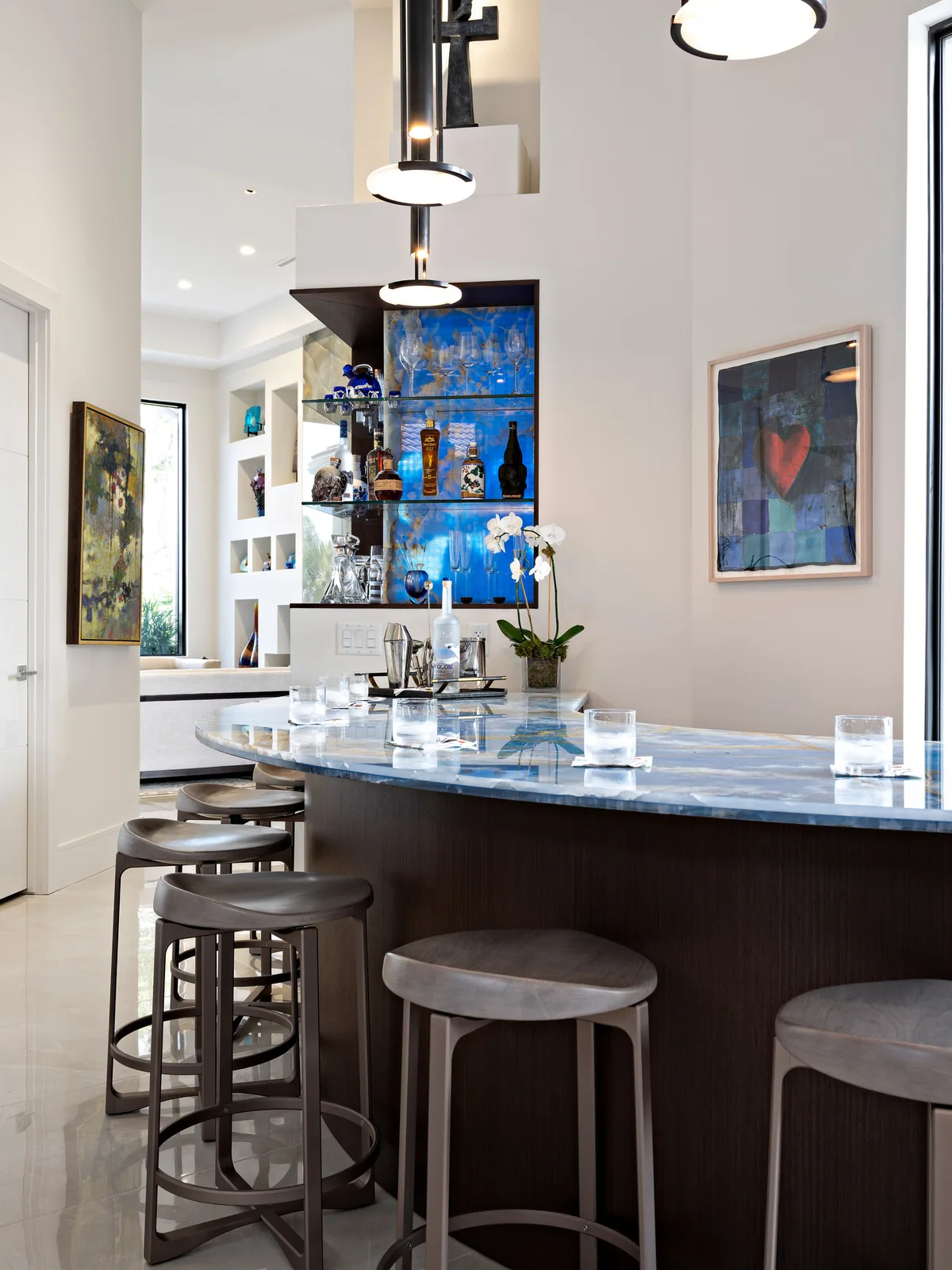Curved custom bar in dark wood with a blue granite top and backlit glass display niche