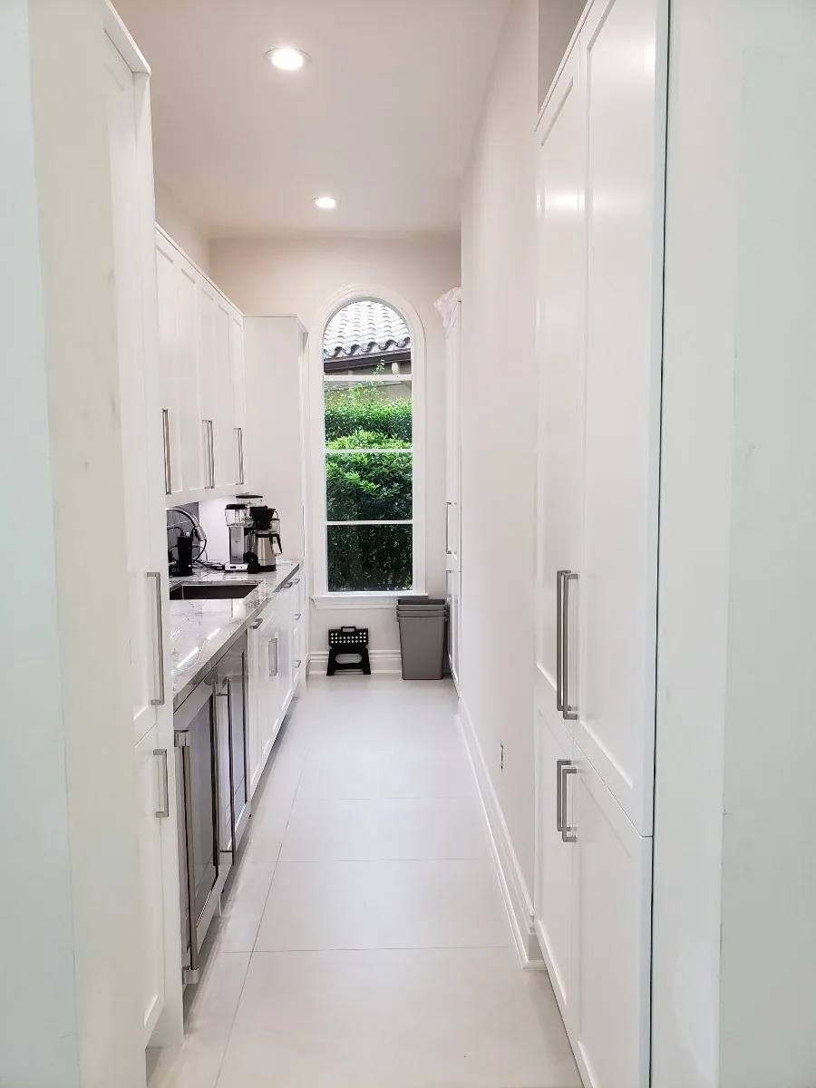 Custom butler's pantry with floor-to-ceiling white cabinetry and full-height storage