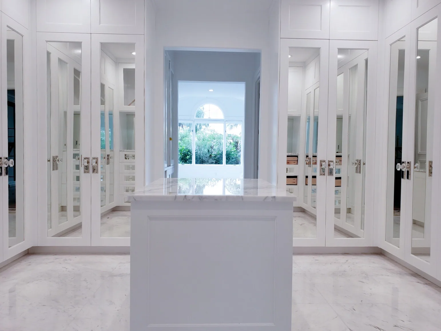Custom dressing room with mirrored cabinet doors and a marble-topped island, Palm Beach County residence, Jupiter FL
