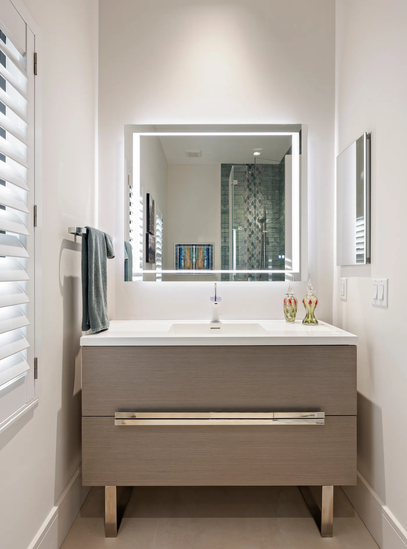 Custom floating vanity in grey oak with an integrated sink and backlit mirror, Palm Beach County residence, Jupiter FL