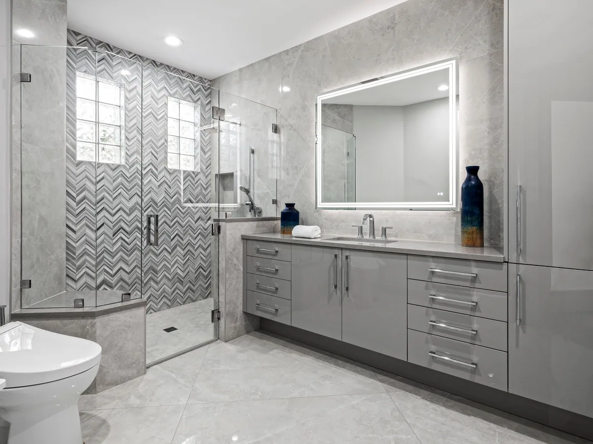 Custom guest bath vanity in grey with a chevron tile walk-in shower, Palm Beach County residence, Jupiter FL