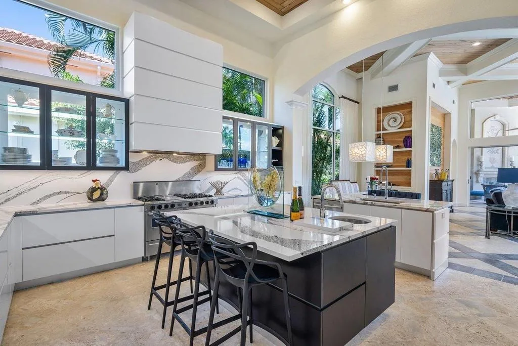 Custom kitchen with a dark stained island, marble counters and integrated hood surround, Palm Beach County residence, Jupiter FL
