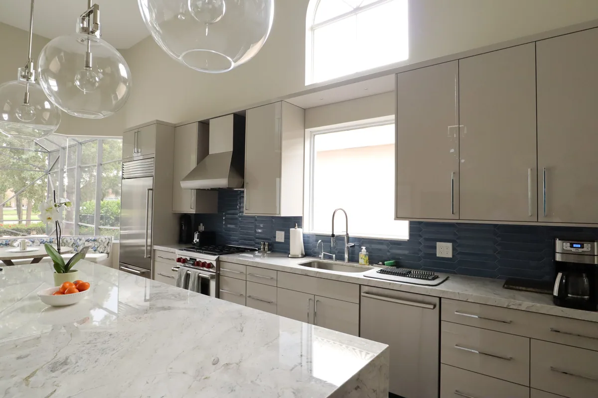 Custom kitchen with a marble waterfall island and navy tile backsplash, Palm Beach County residence, Jupiter FL