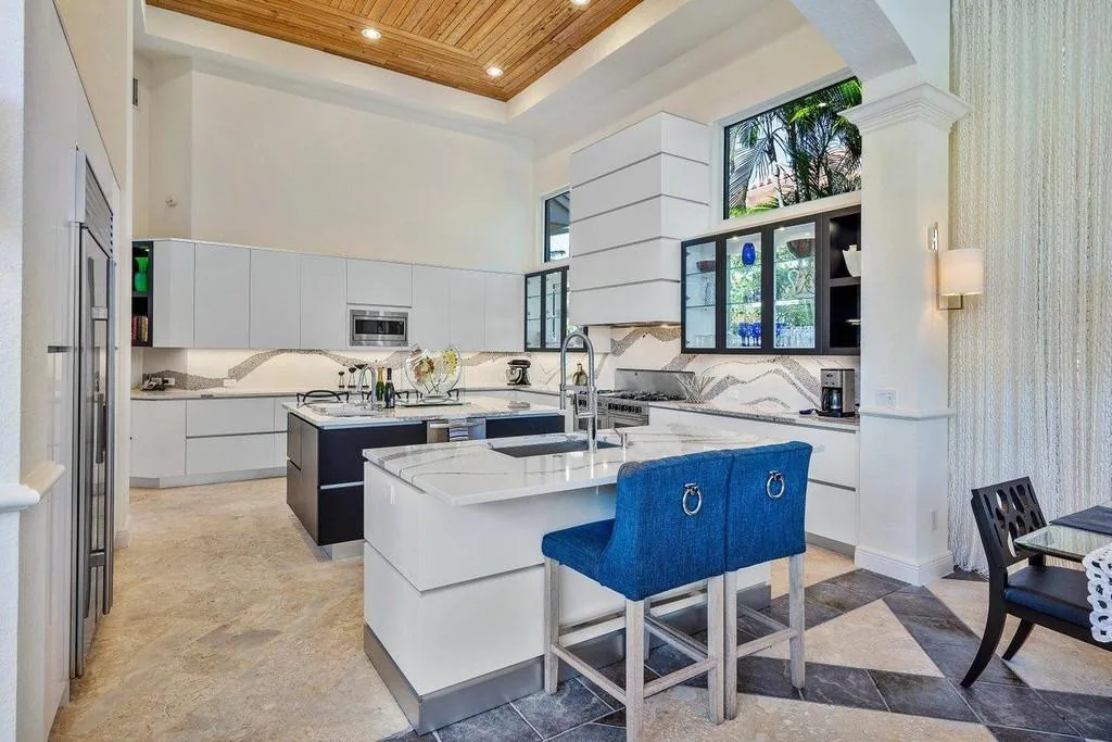 Custom white kitchen with a planked wood tray ceiling and blue upholstered counter stools, Palm Beach County residence, Jupiter FL