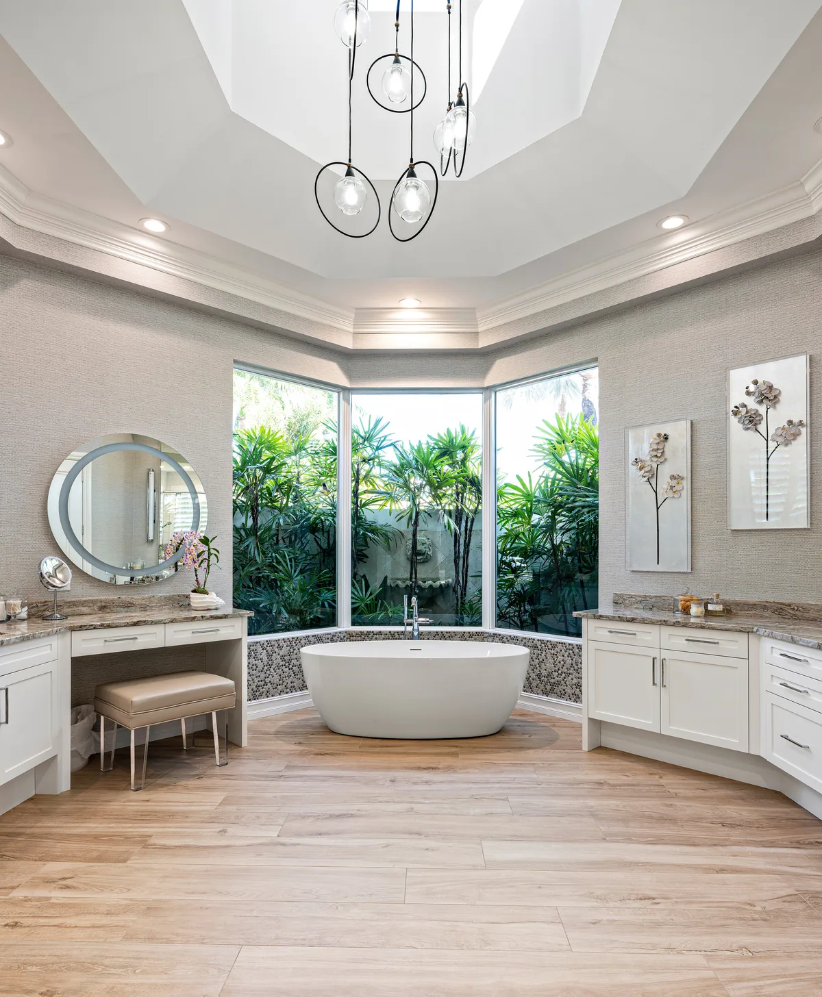 Custom primary bath with white painted vanity, seated makeup station and a freestanding tub in the bay window, Palm Beach County residence, Jupiter FL