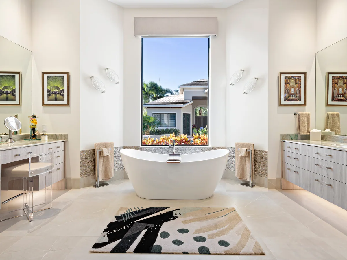 Custom primary bath with facing dual vanities, a pebble-tile tub surround and a centered freestanding tub, Palm Beach County residence, Jupiter FL