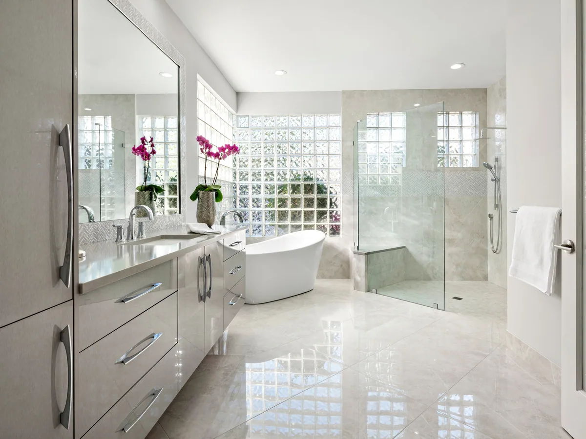 Custom primary bath vanity in grey with a freestanding tub and glass walk-in shower, Palm Beach County residence, Jupiter FL